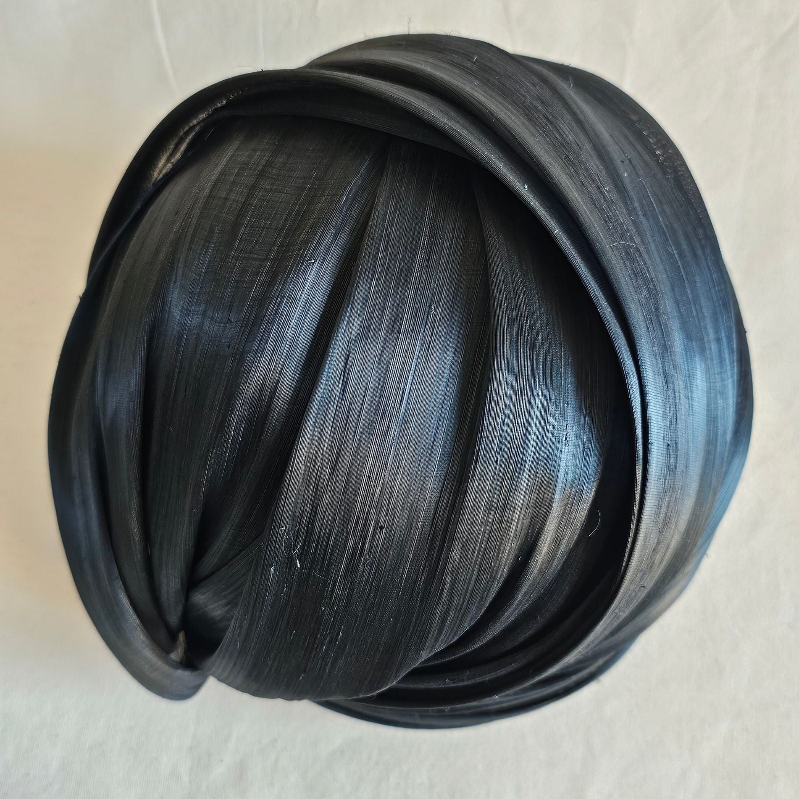 Black silk abaca turban hat with beautiful sheen, top view.