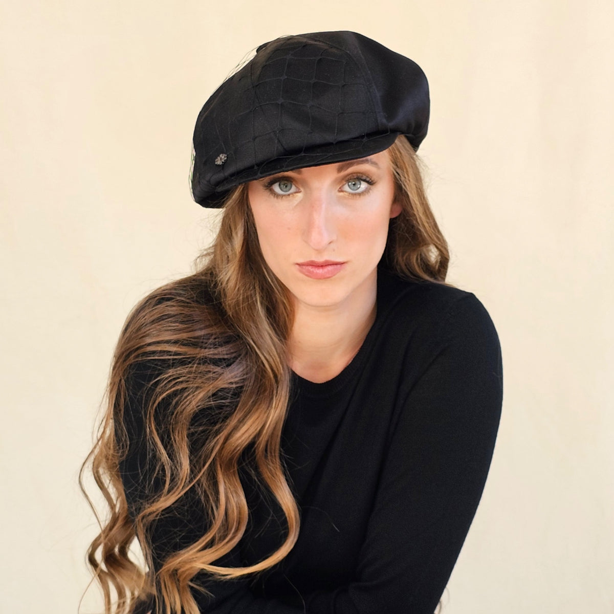 Front view of black silk satin baker boy cap with subtle net veil.