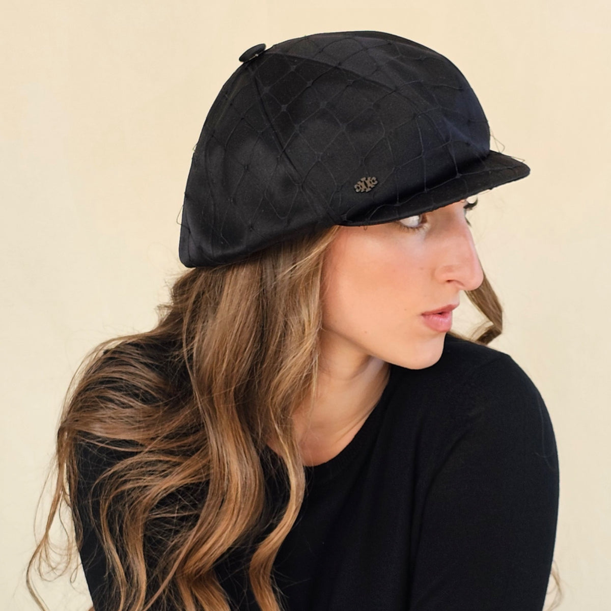 Side close-up of black silk satin baker boy cap showing net veil and
short peak.