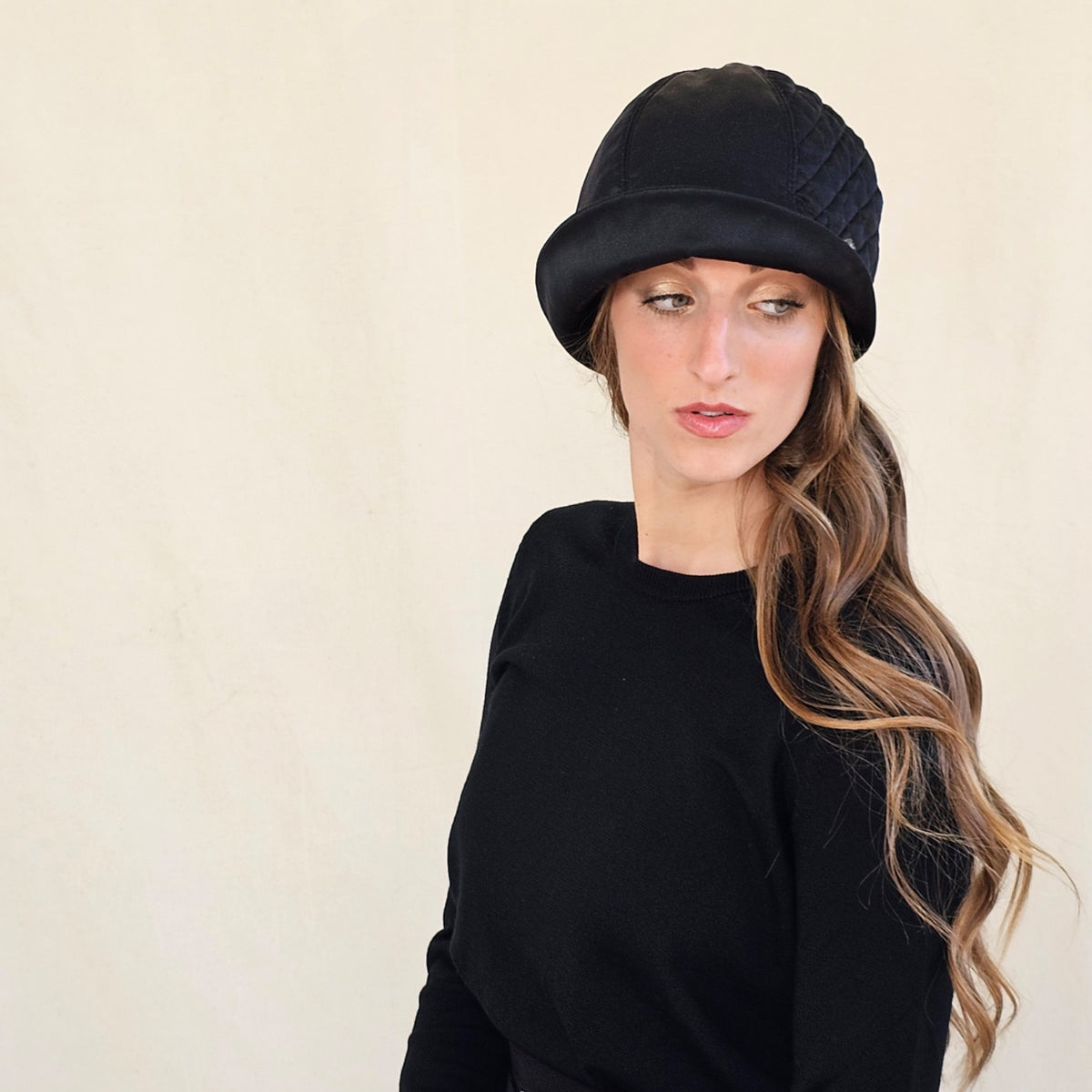Black silk satin cloche with quilted panel, worn on a model.