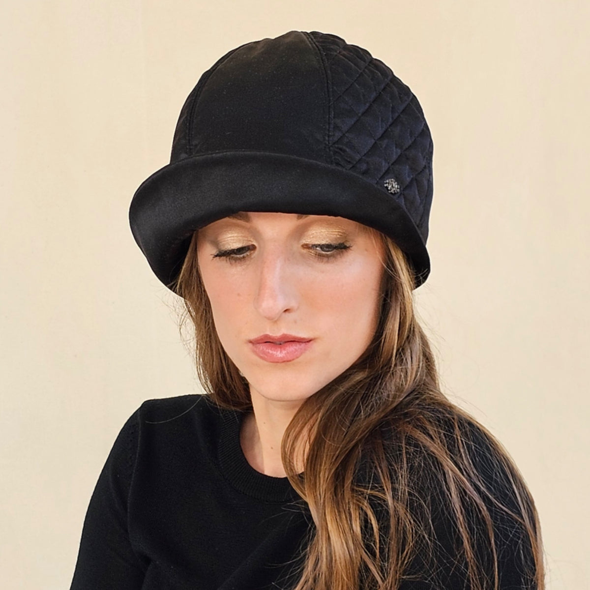 Close-up of black silk satin cloche showing diamond-quilted panel.