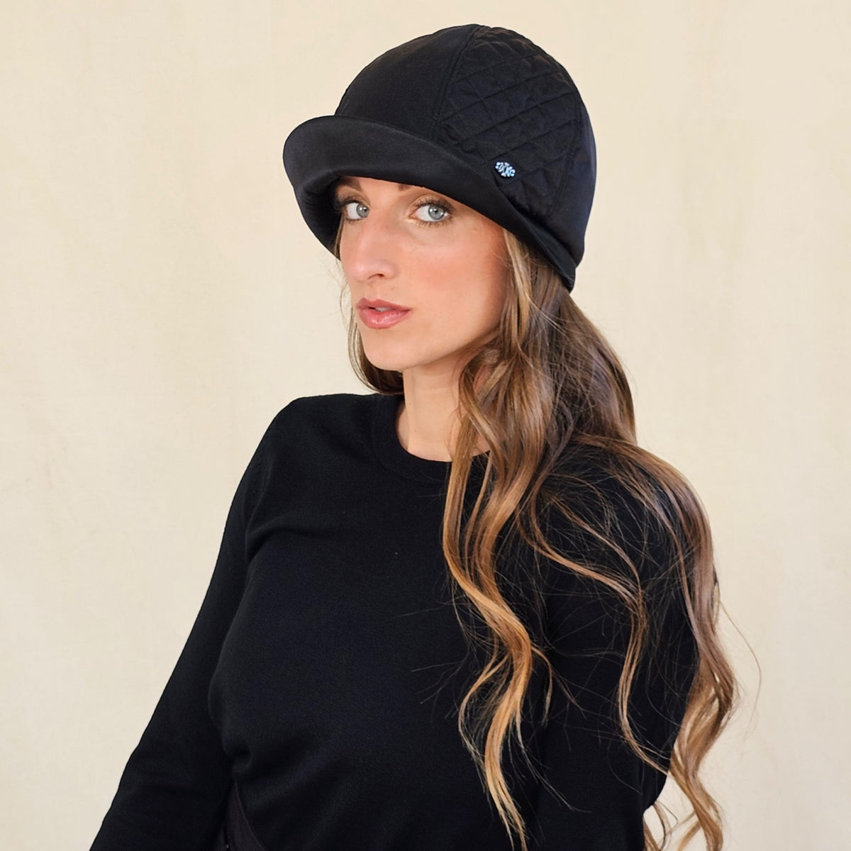 Angled view of black silk satin cloche with quilted panel and curved
brim.
