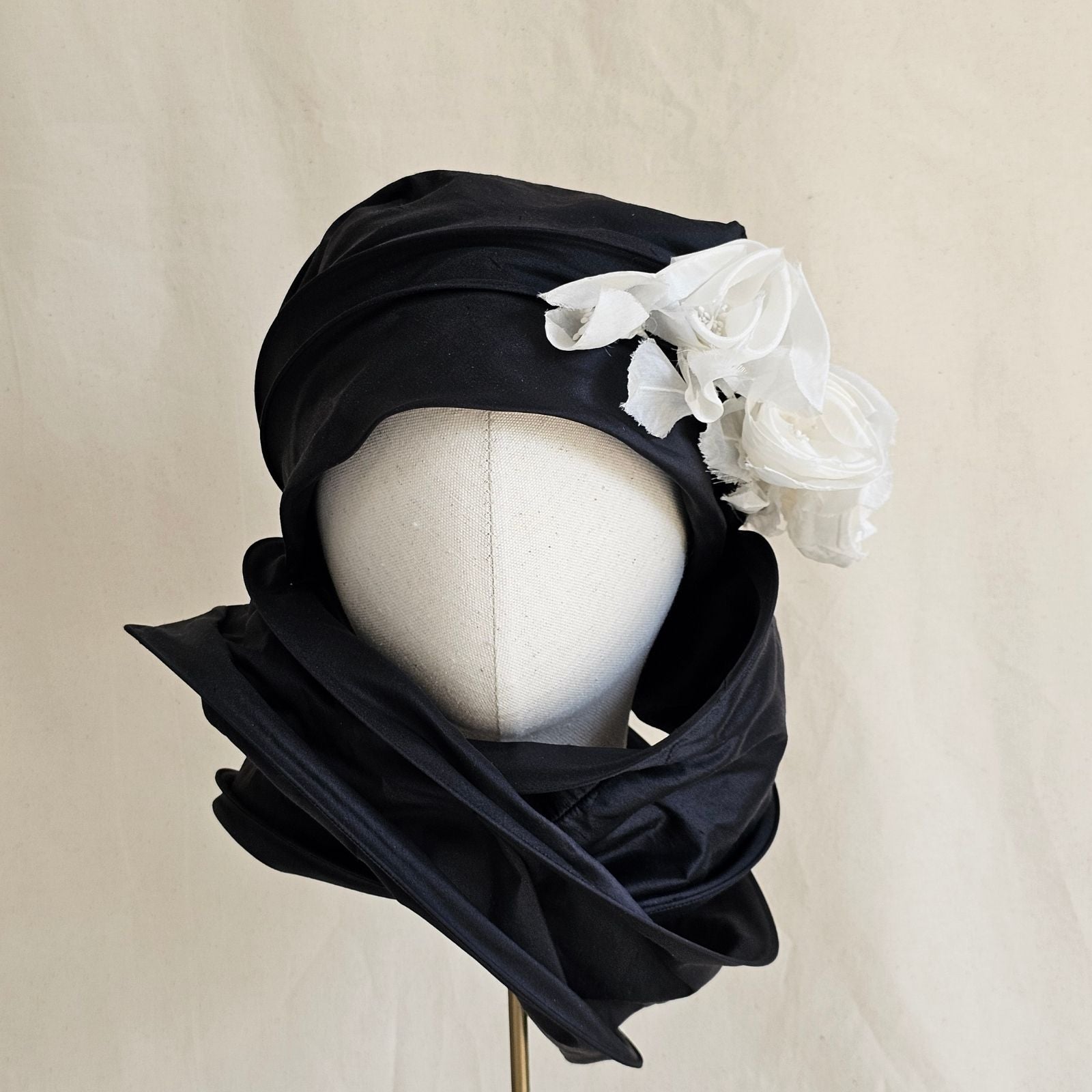 Black silk scarf turban with delicate ivory flowers, wrapped front view.
