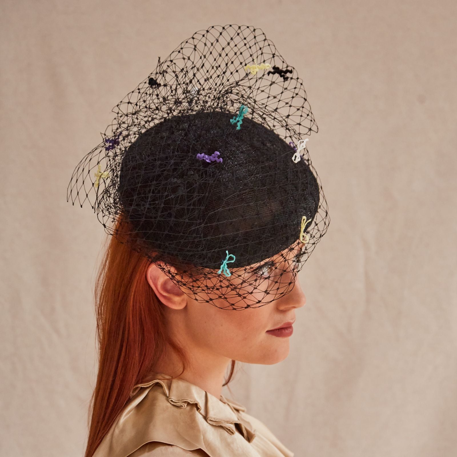 Black sinamay beret with intricate black veiling and multicolour bow detailing, right view.