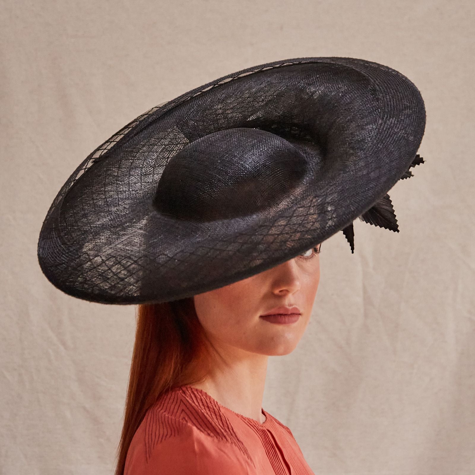 Black sinamay disc hat with crin embellishment and elegant underside feathers, right view.
