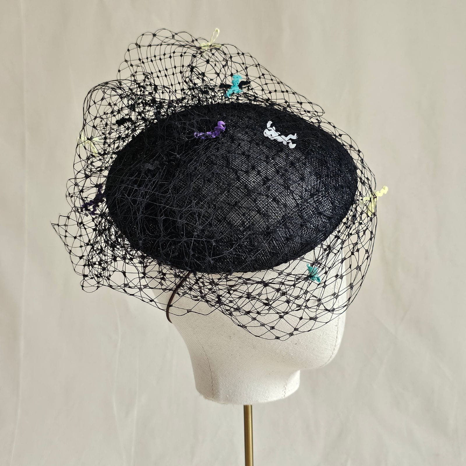Black sinamay beret with beautiful veil and multicolour bow detailing, right view.