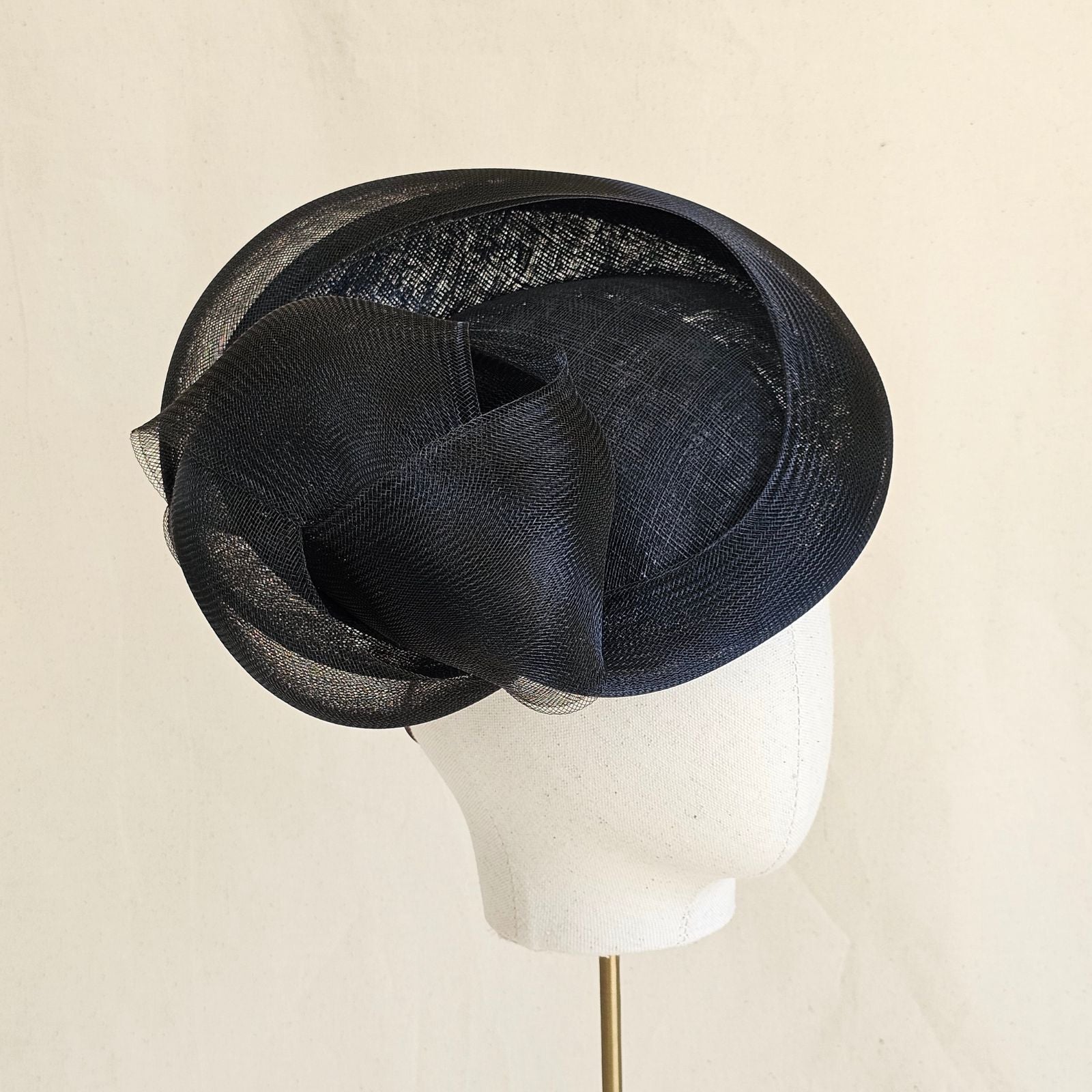 Black straw disc hat with sculptural crin knot, side view.