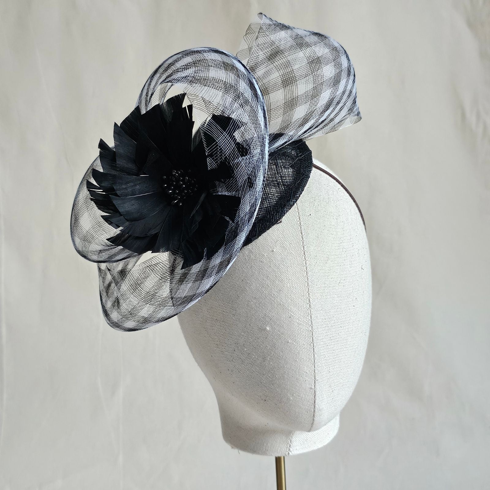 Fascinator with black and white check crin swirl and beautiful black flower, front view.