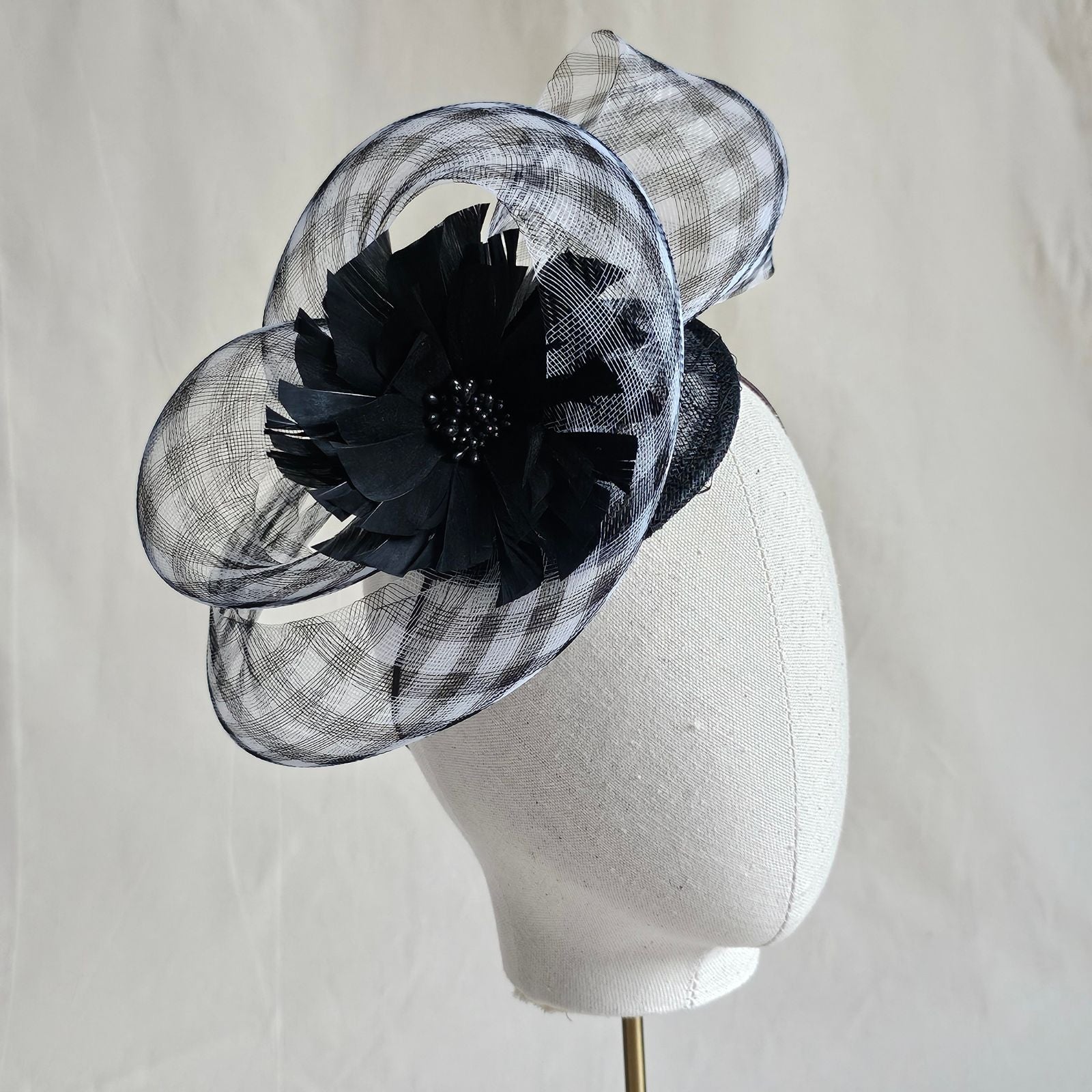 Fascinator with black and white check crin swirl and beautiful black flower, side view.
