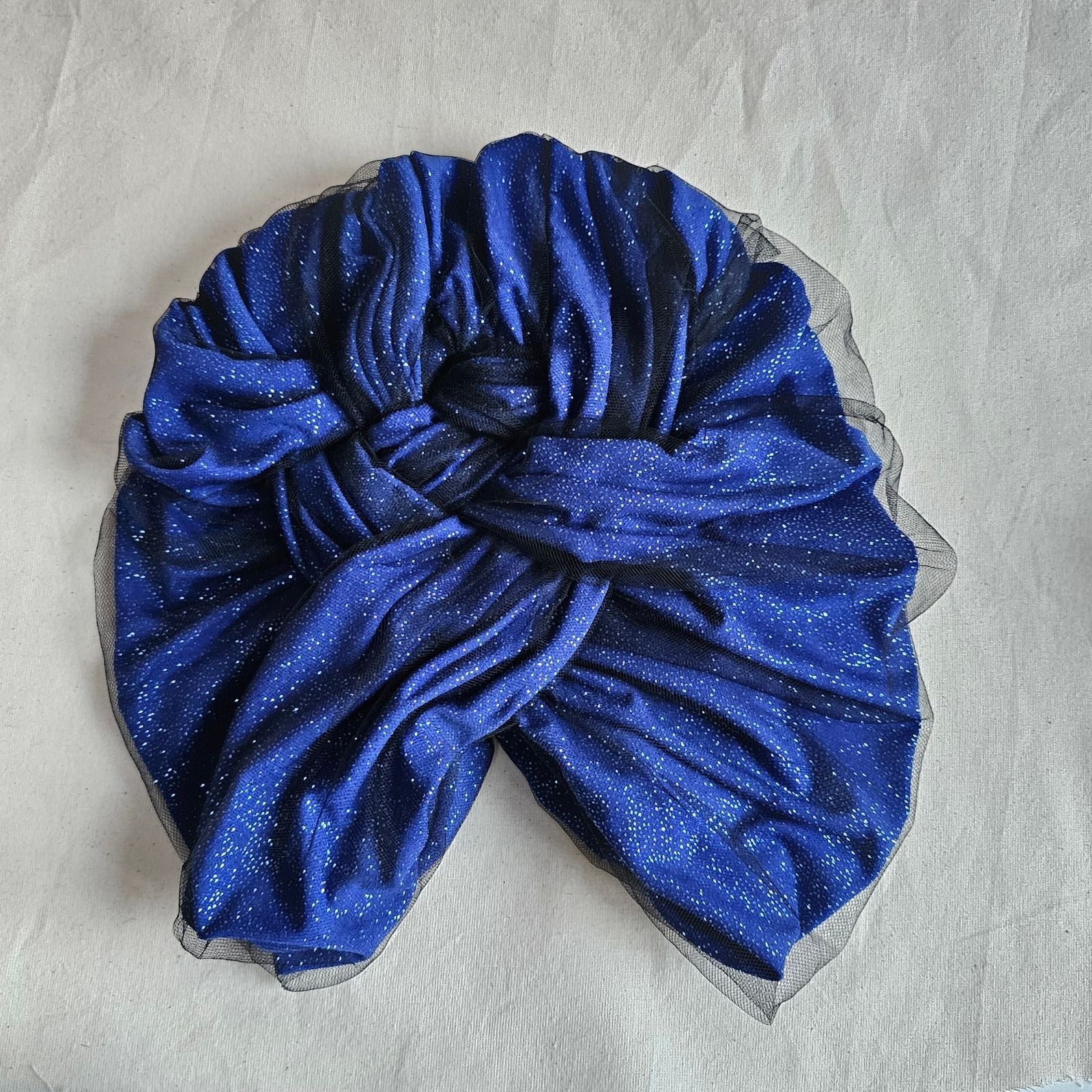 Blue sparkle tulle intricately braided turban, top view.