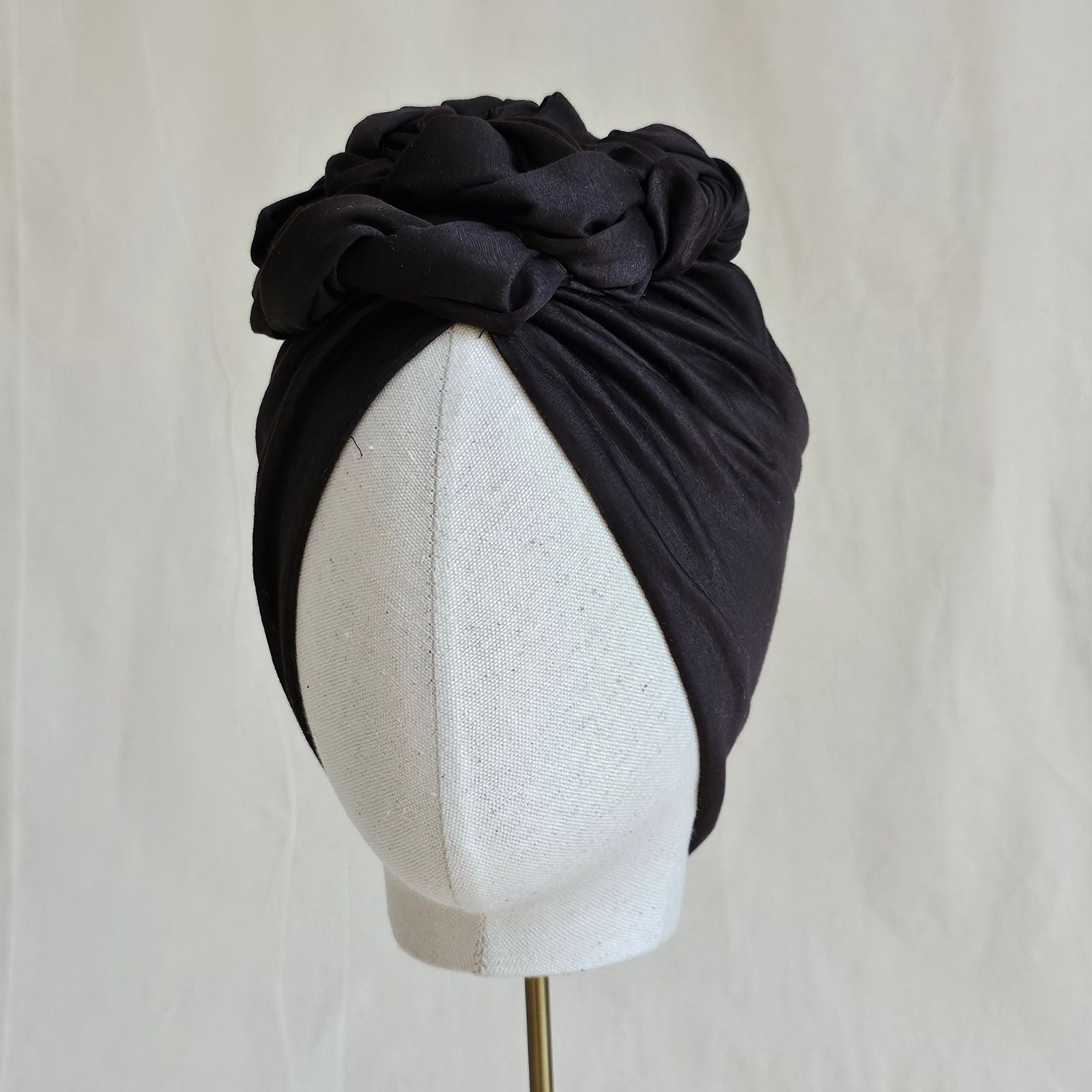 Brown cotton turban loosely gathered into intricate braid design, front view.