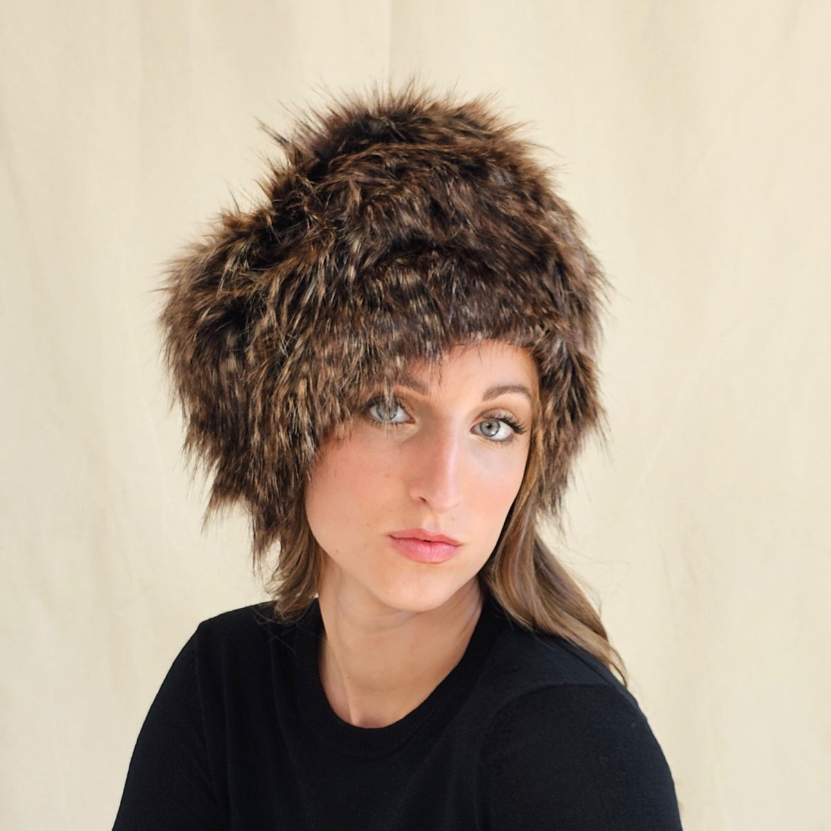 Front view of brown and black faux fur pillbox hat on a seated
model.