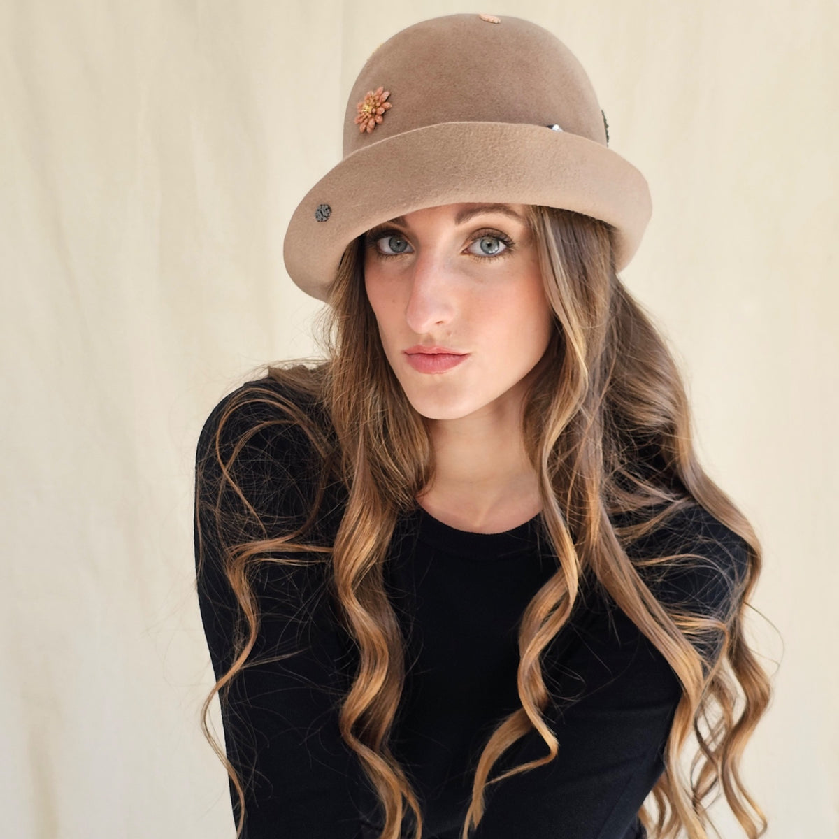 Camel felt cloche with a flower motif on the crown, angled view.