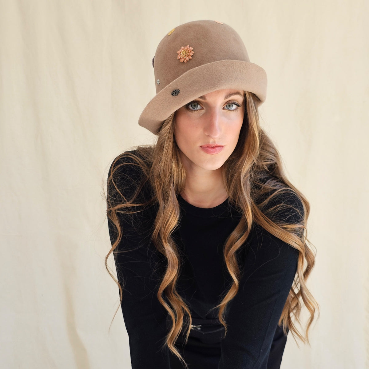 Camel felt cloche with flower and monogram embellishments,
worn on a model.
