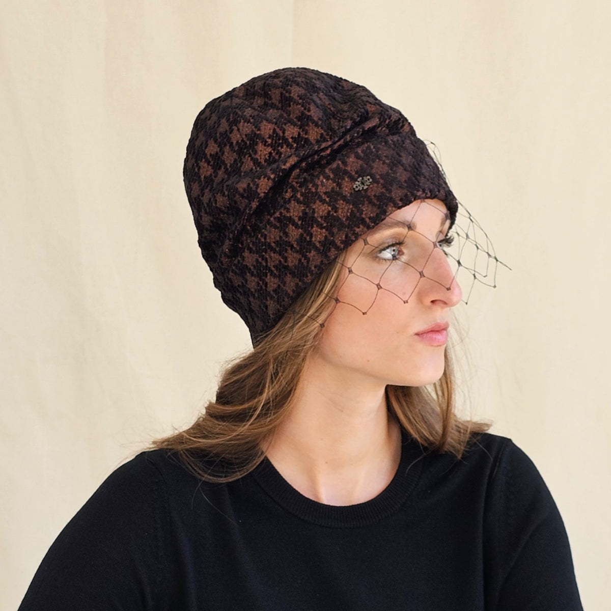 Side view of brown houndstooth beanie showing the projecting
black veil.