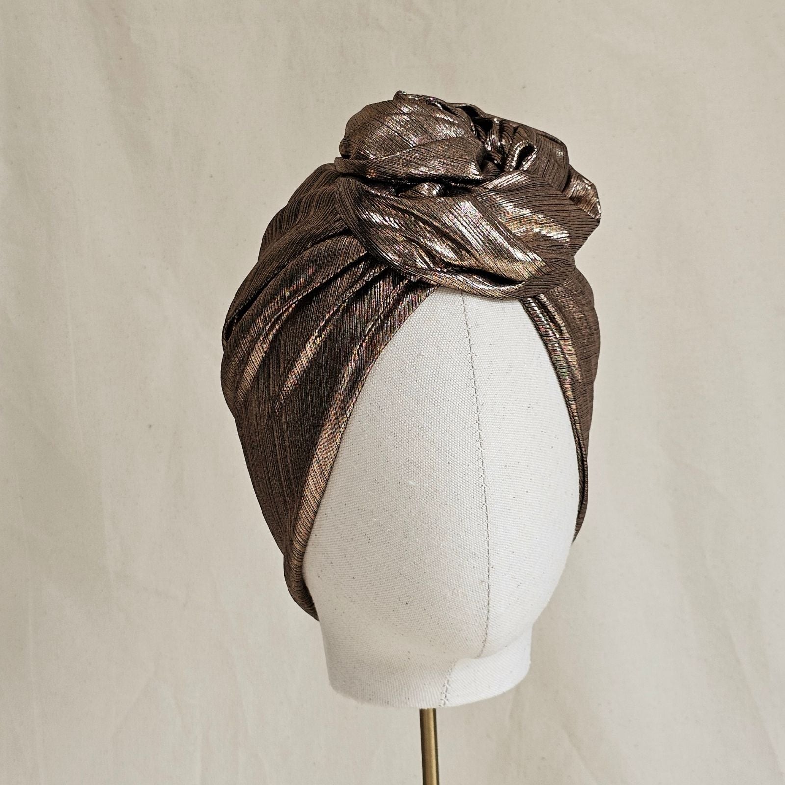 Copper lamé turban with sculptural rose knot, front view.
