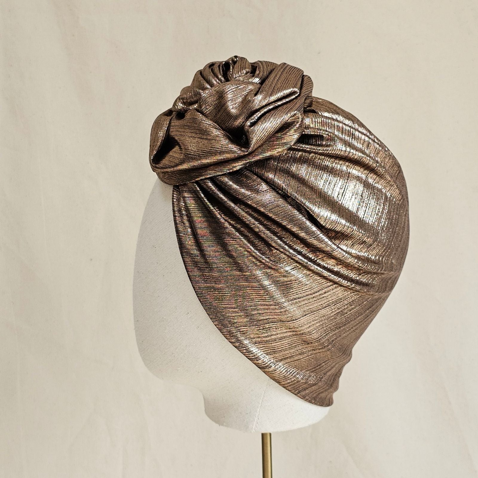 Copper lamé softly gathered turban with beautiful knotted rose, side view.