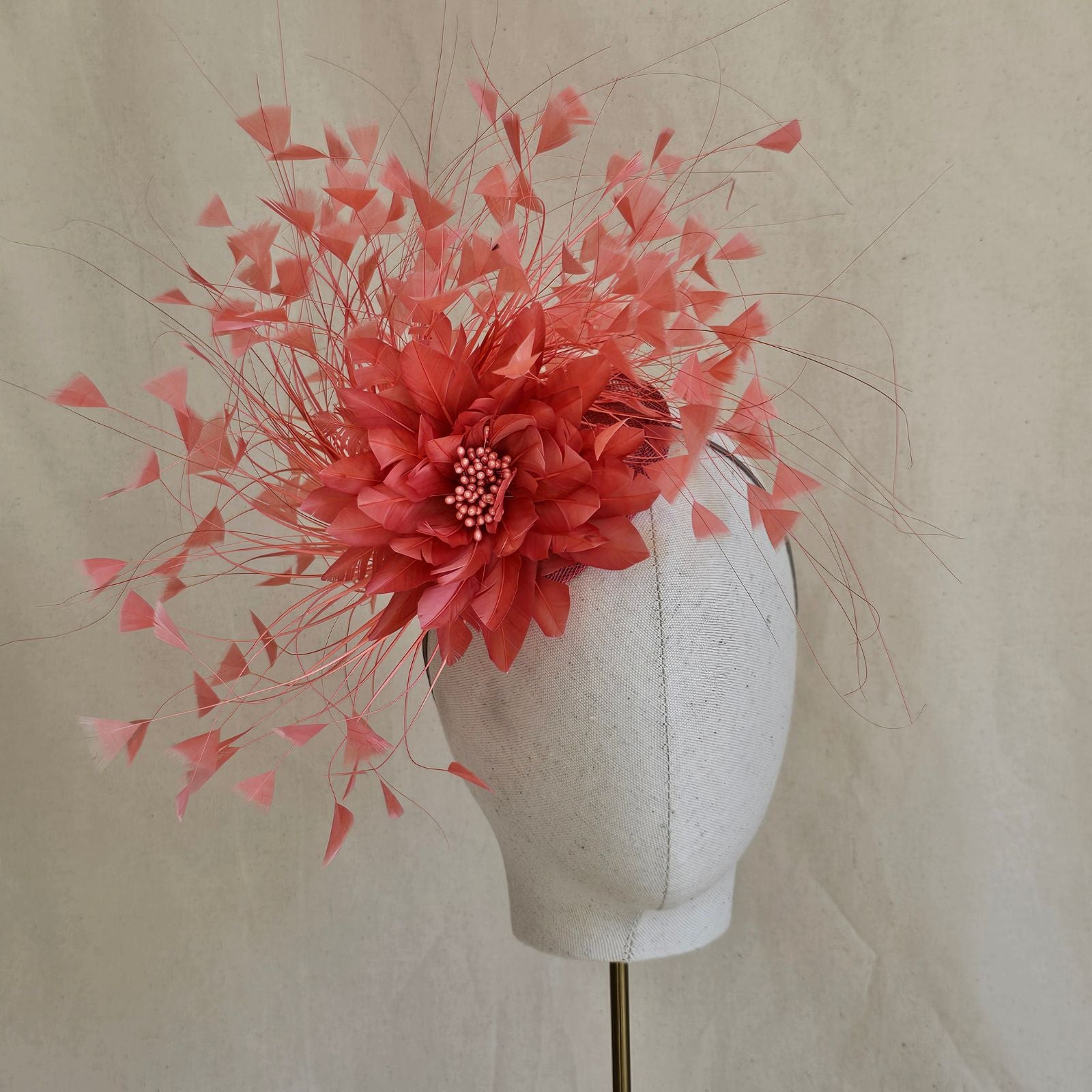 Coral feather fascinator with feather flower, front view.