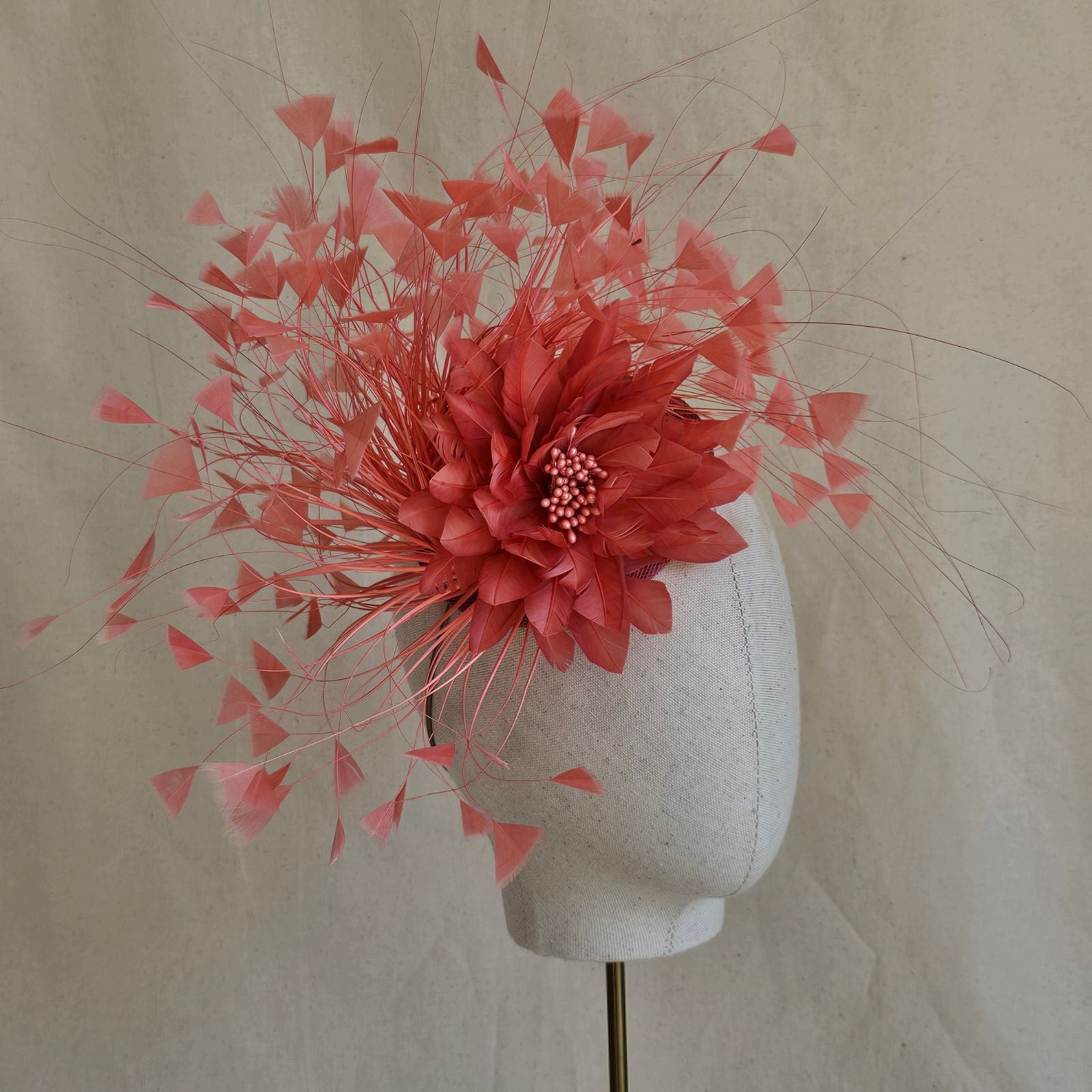 Coral feather fascinator with feather flower, side  view.