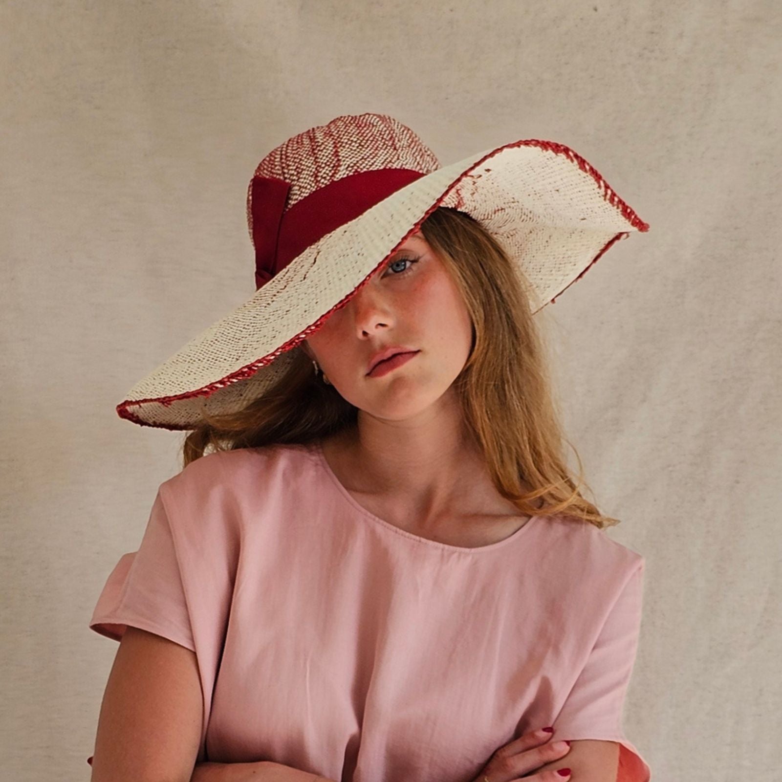 Cream and red straw sunhat with stylish ribbon, front view.