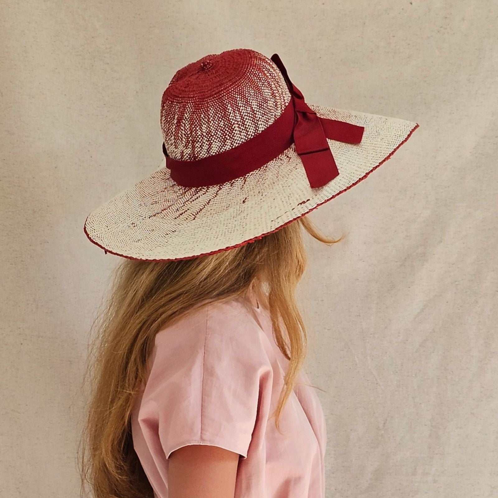 Cream and red straw sunhat with stylish ribbon, rear view.