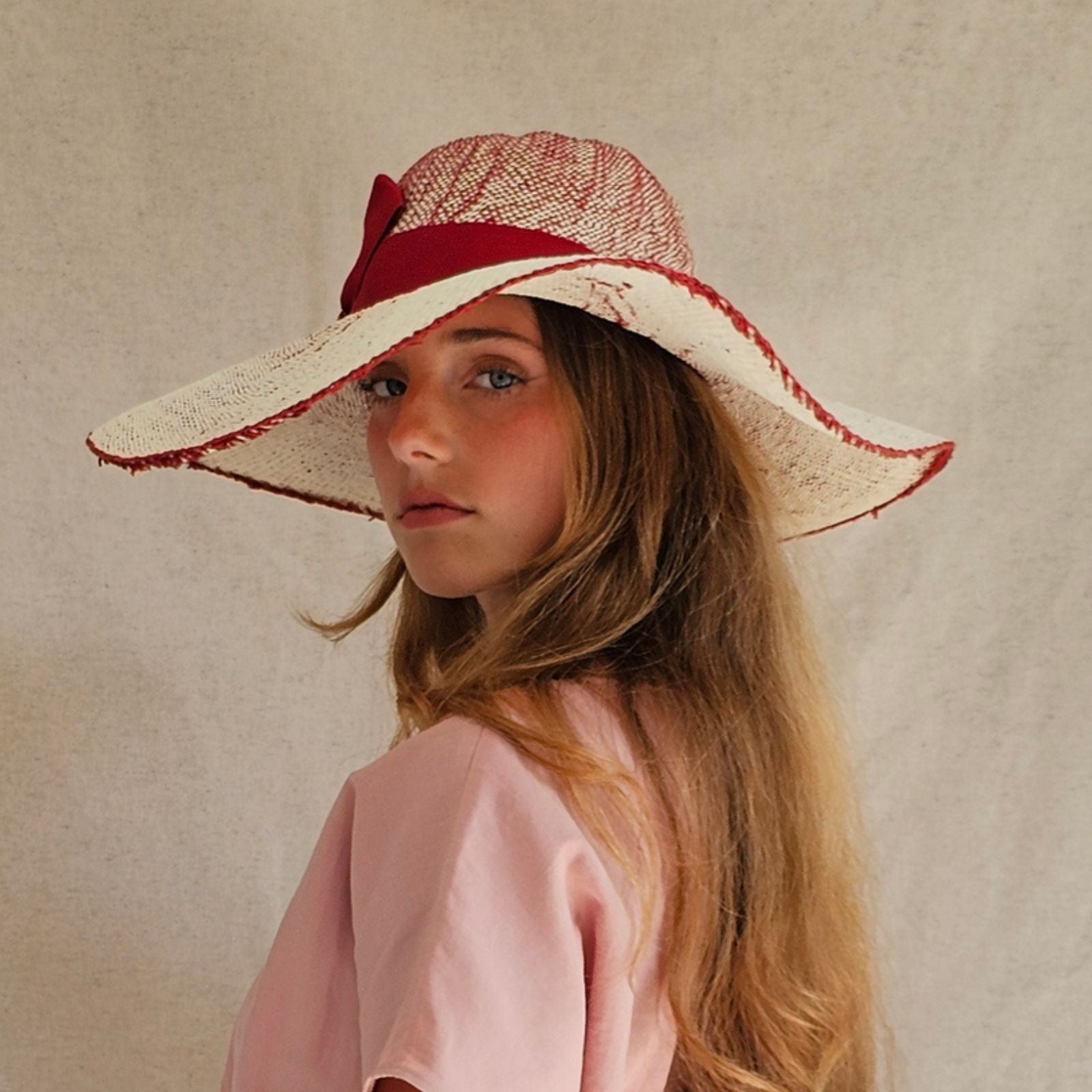 Cream and red straw sunhat with stylish ribbon, side view.