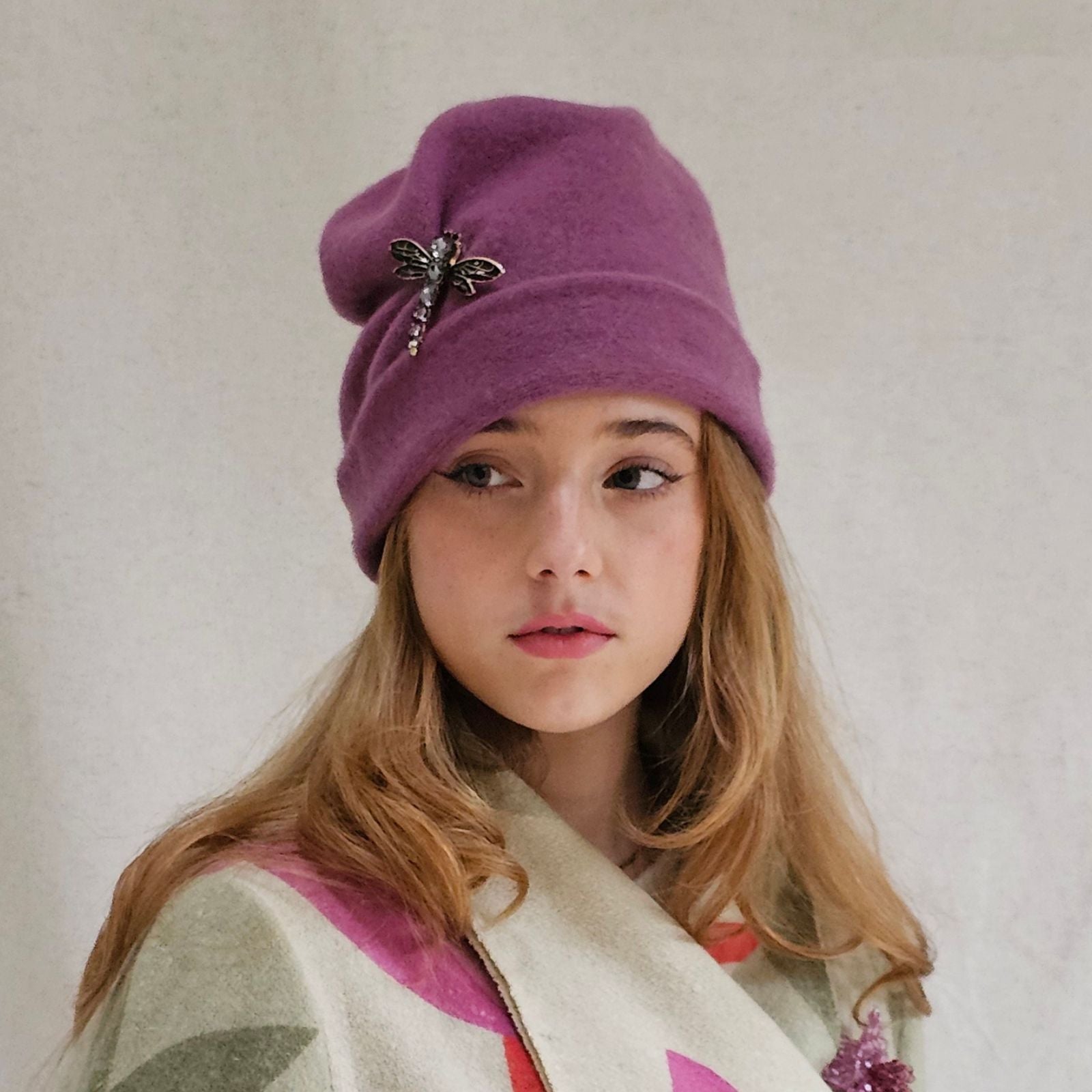 Dusky pink wool beanie with beautiful dragonfly brooch, front view.