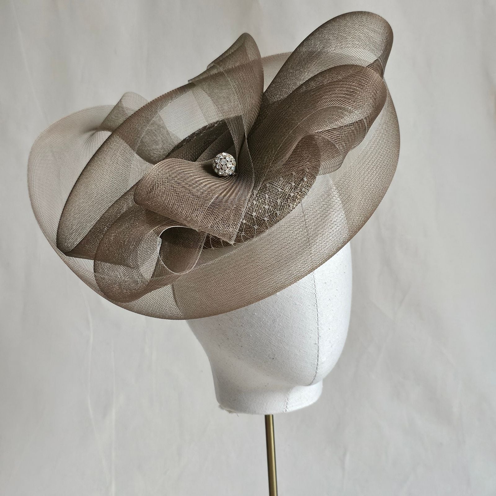 Gold fascinator with elegant crin swirls and crystal diamanté globe embellishment, angle view.