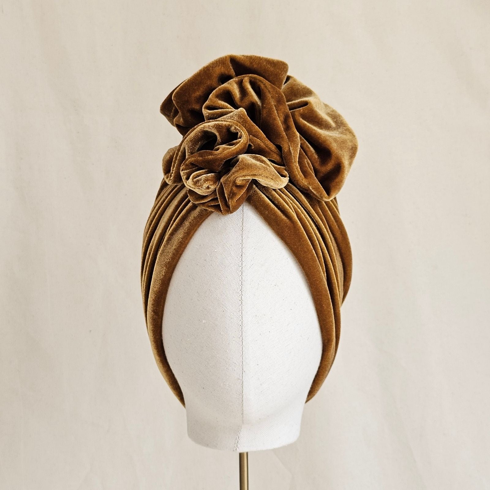 Gold velvet turban gathered into elegant ruffle, front view.