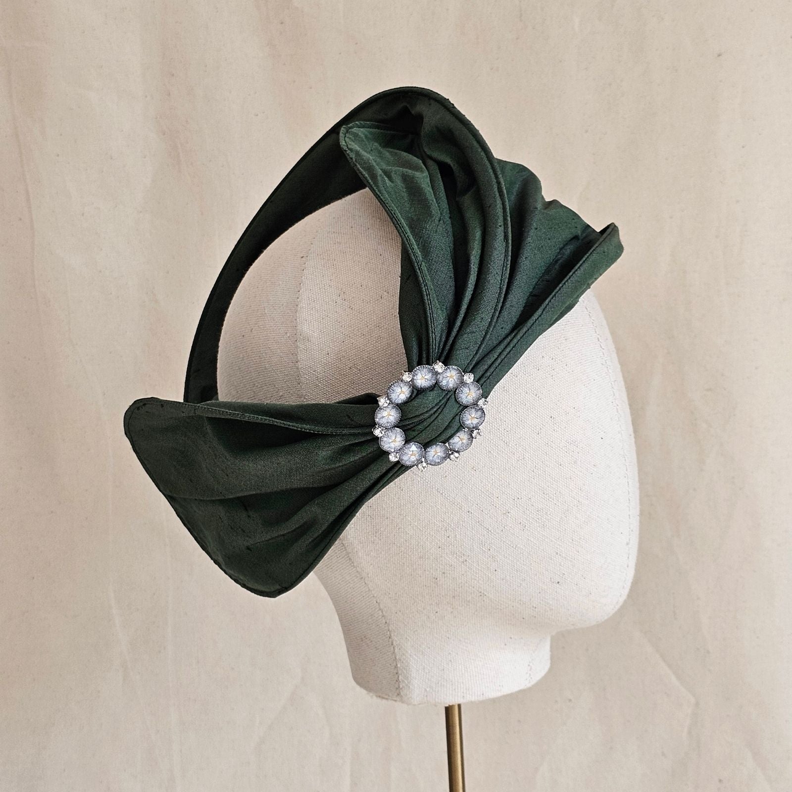 Green silk head wrap with decorative brooch, side view.