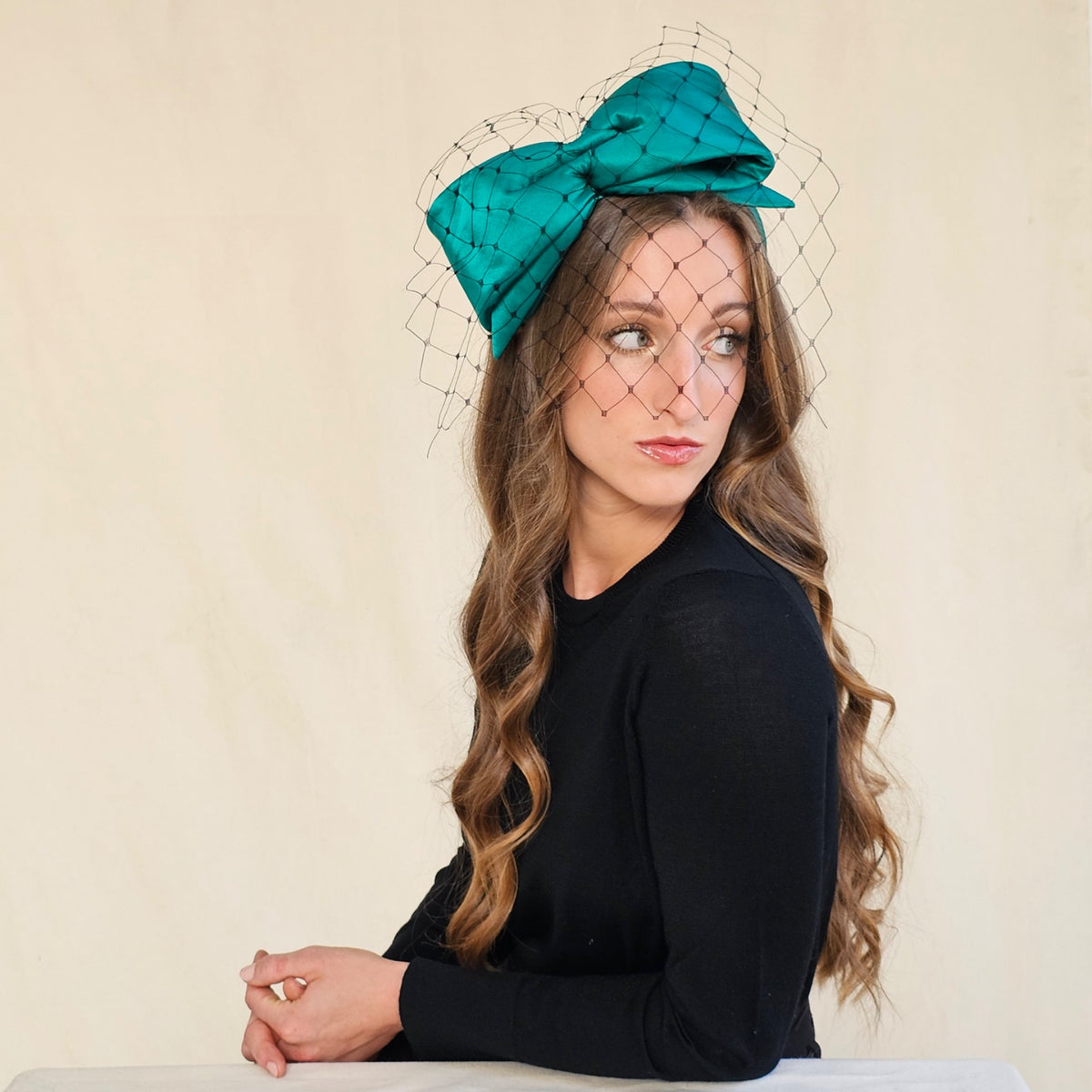 Emerald silk bow headband with black face veil, worn on a model.