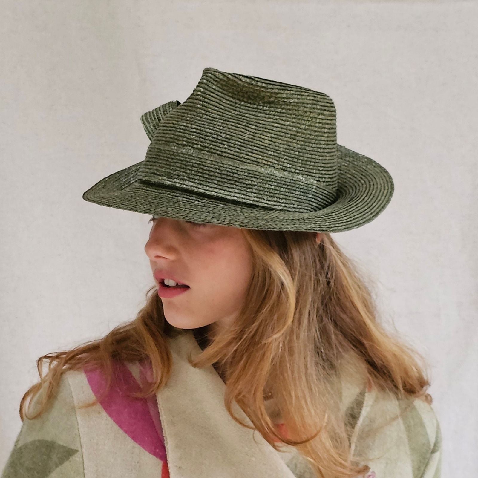 Green straw trilby with elegant bow swirl, left view.