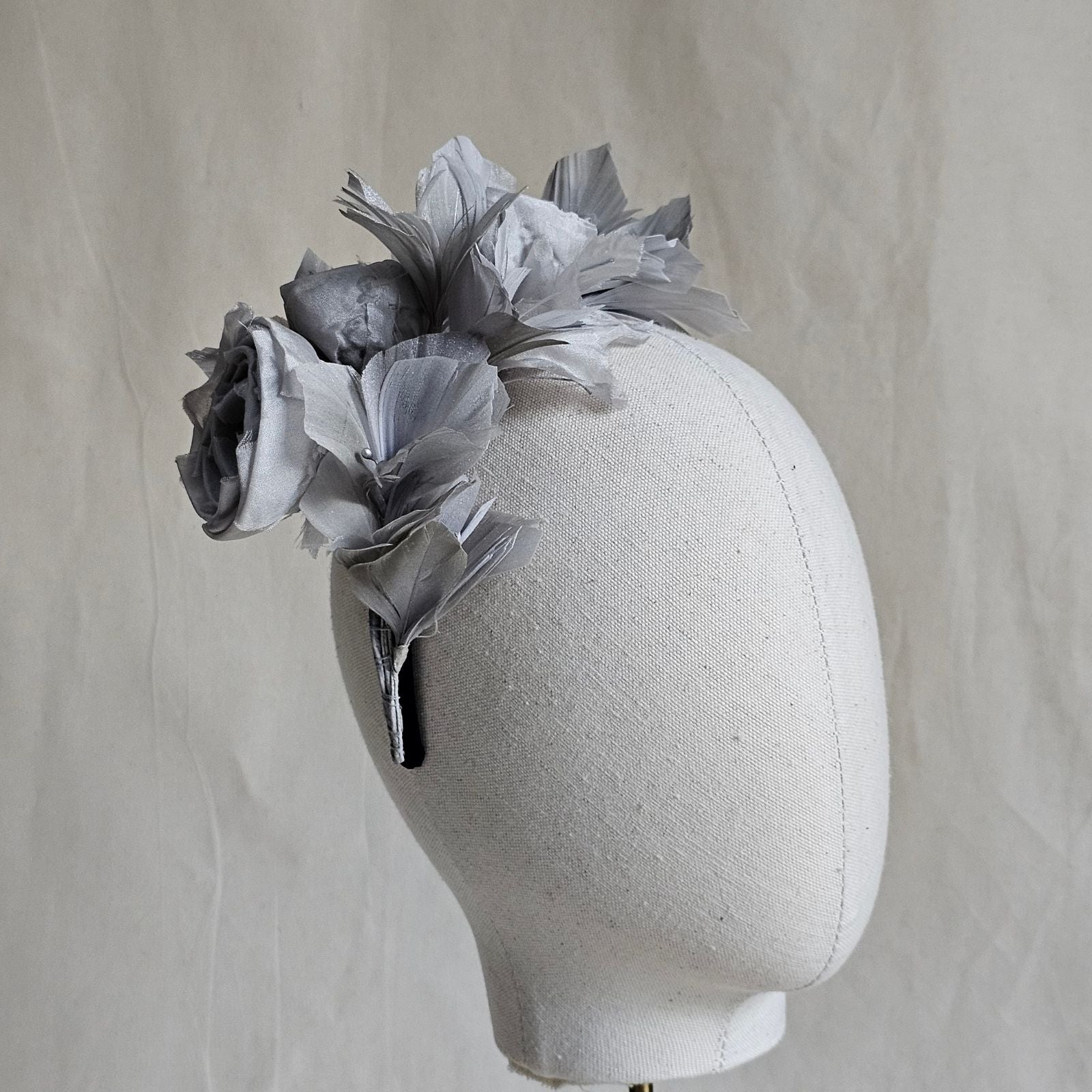 Headband with grey bud roses and feather flowers, side view.