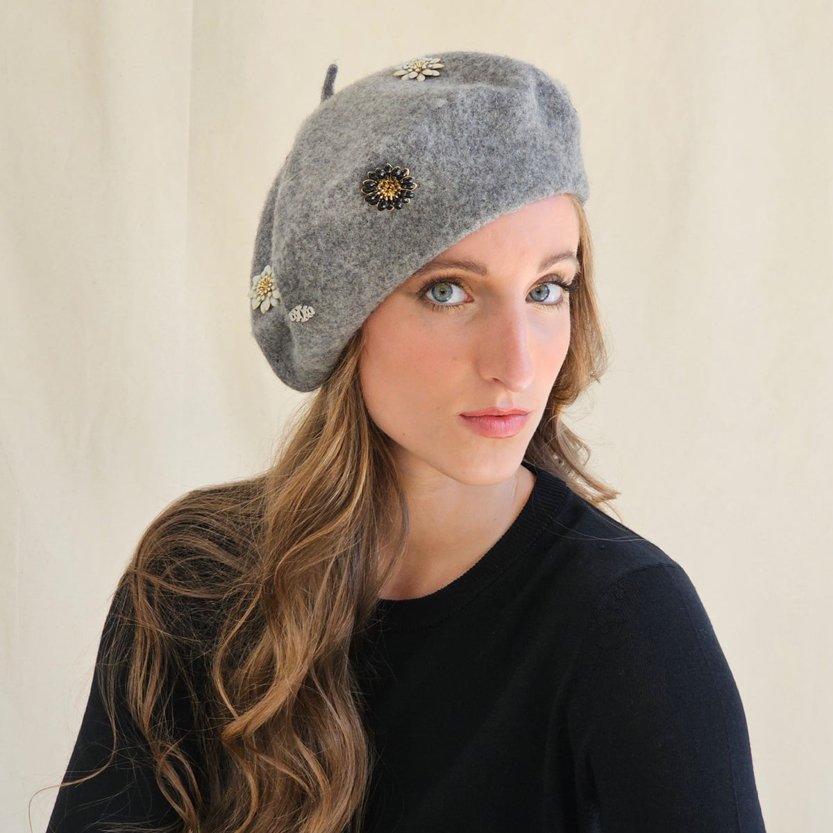 Grey wool beret with flower and monogram embellishments, worn
tilted on a model.