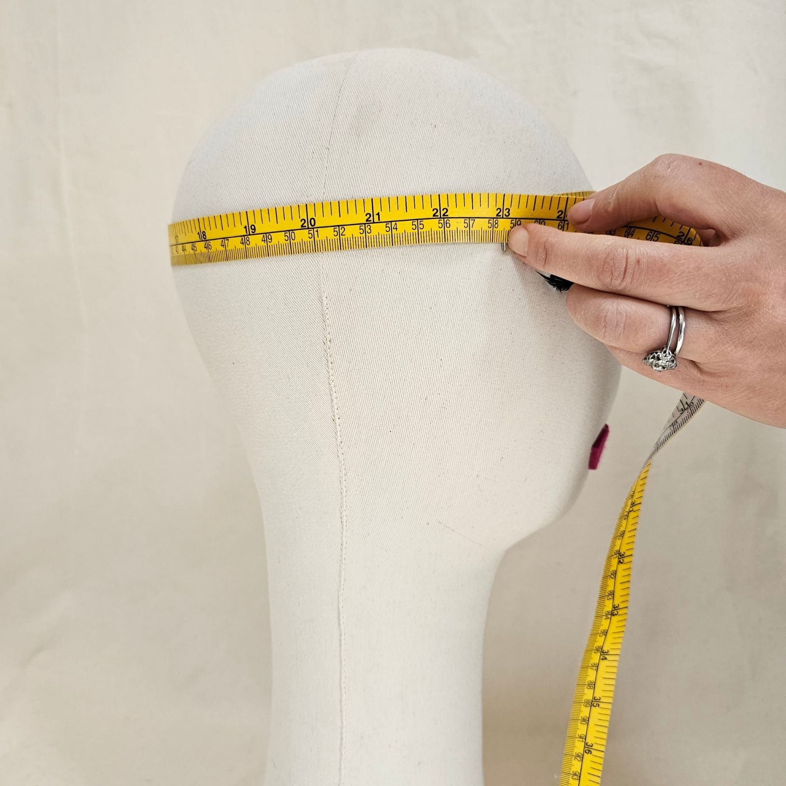 Tape measure placed around a mannequin head to show how to measure for a hat.