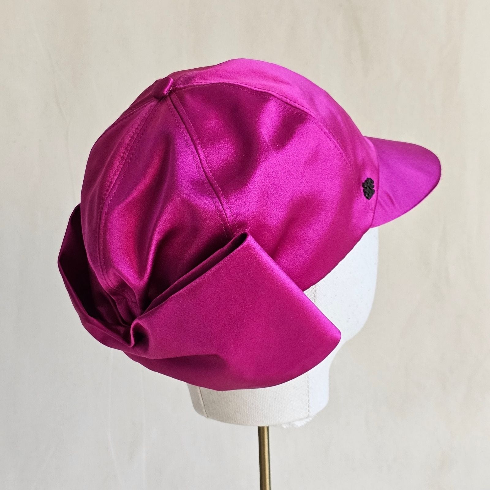 Hot pink silk baseball cap with dramatic bow, side view.