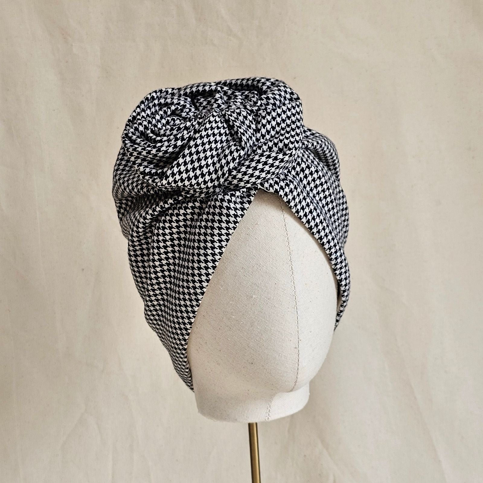 Houndstooth softly gathered turban with sculpted rose knot, front view.
