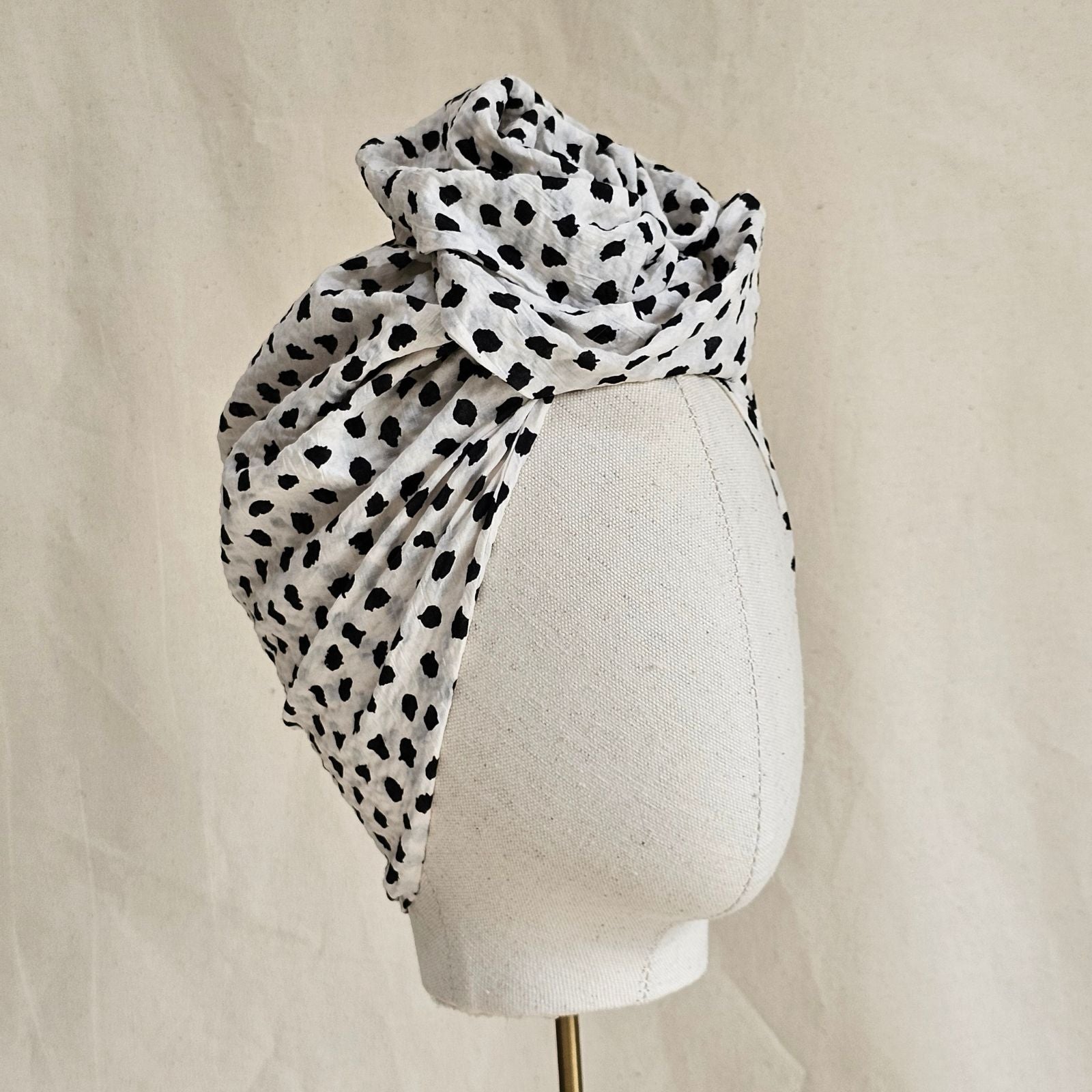 Ivory cotton turban with black dot print and beautiful knotted rose, angle view.