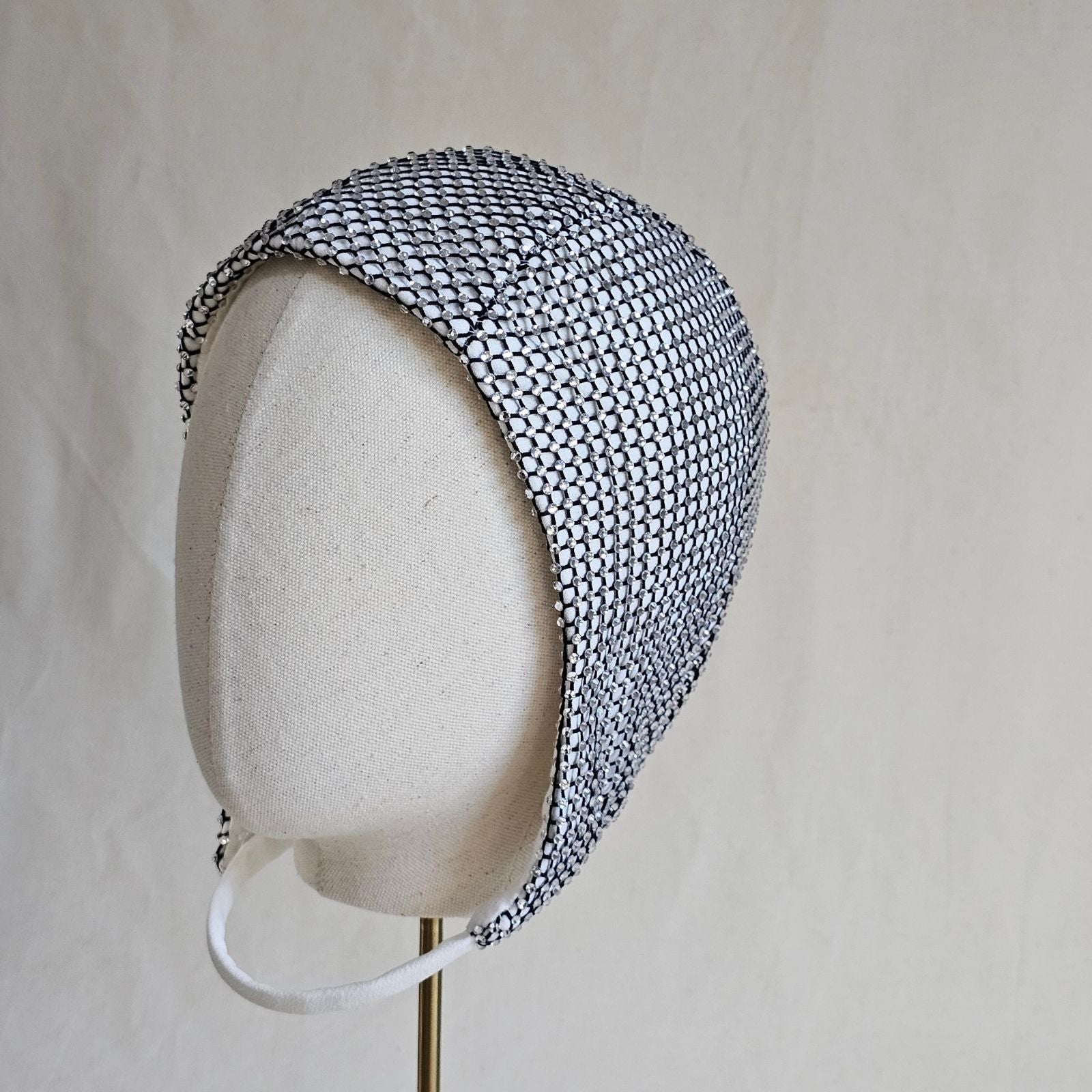 Ivory aviator cap with intricate crystal mesh, left view.