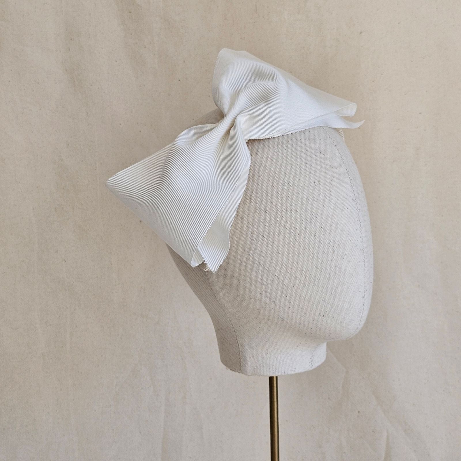 Ivory wide petersham bow on a headband, side view.