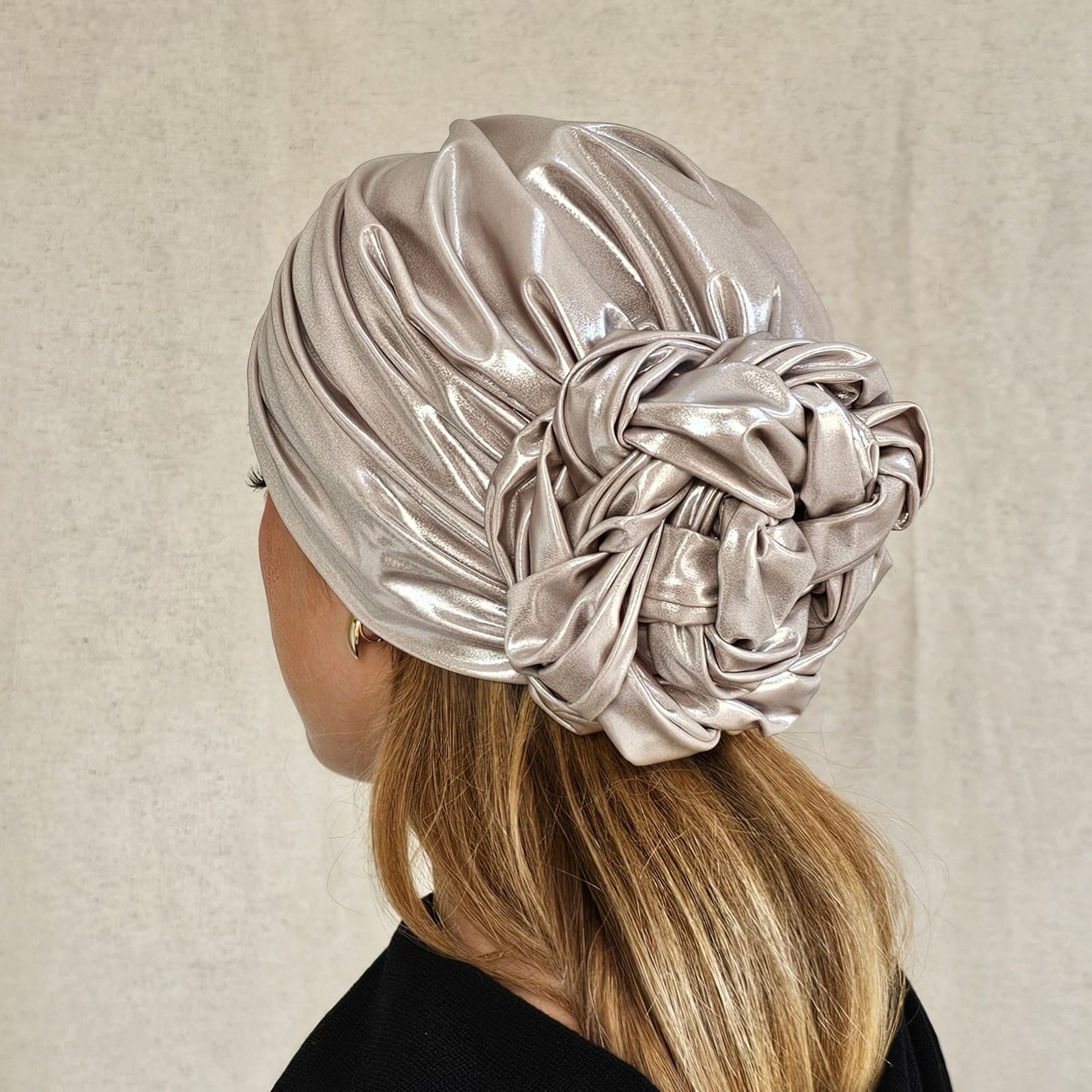 Ivory sparkly designer turban gathered into intricately plaited flower knot, rear view.