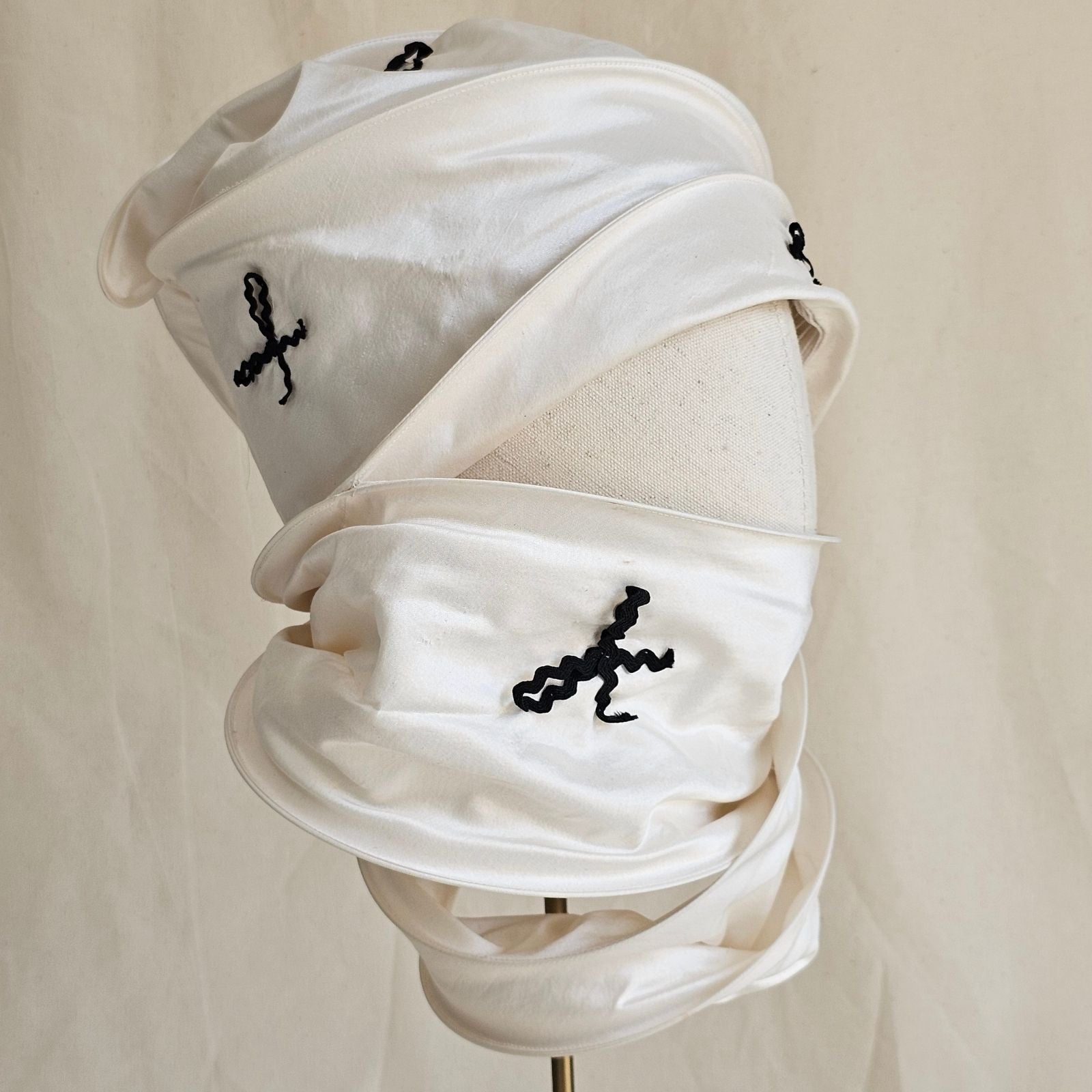 Ivory silk scarf turban with black bow detailing, right side view.