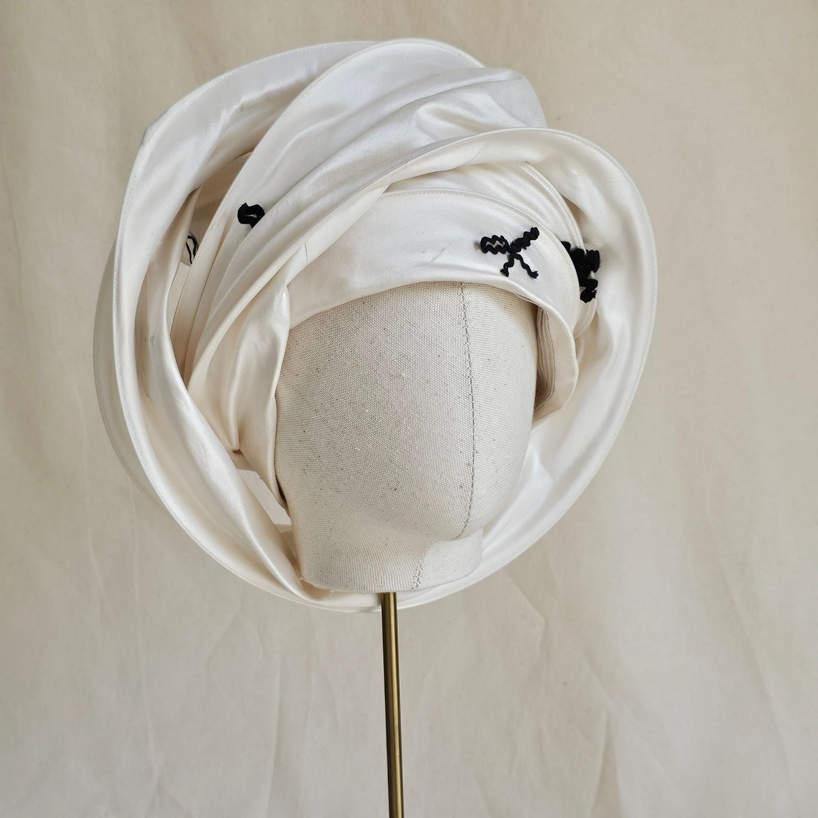 Ivory silk scarf turban with black bow detailing, wrapped angle view.