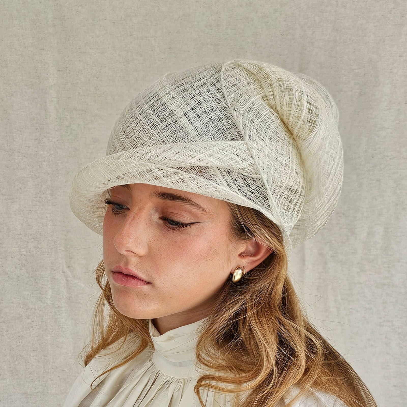 Ivory sinamay sculptural cloche hat, side view.
