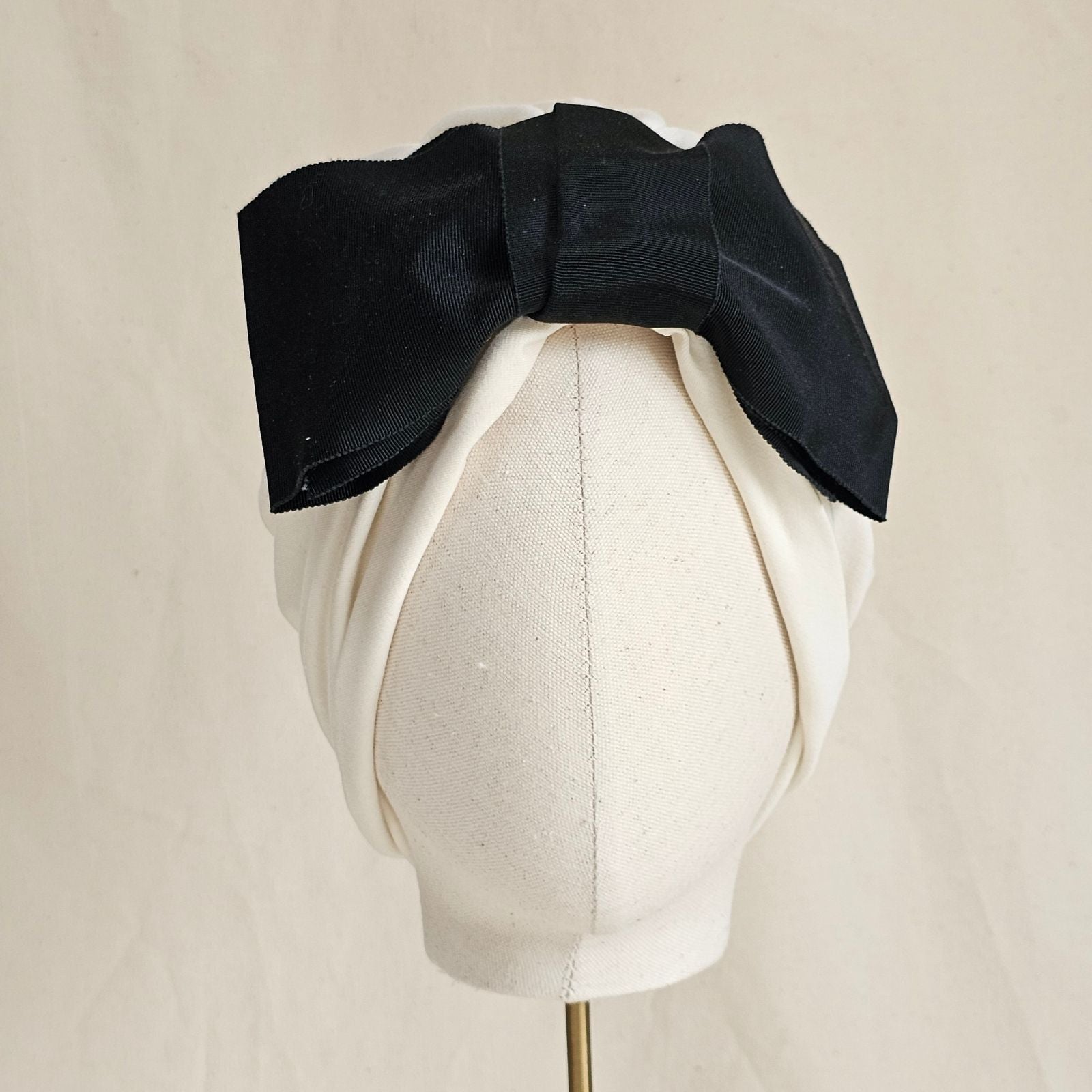 Ivory turban with dramatic black petersham bow, front view.