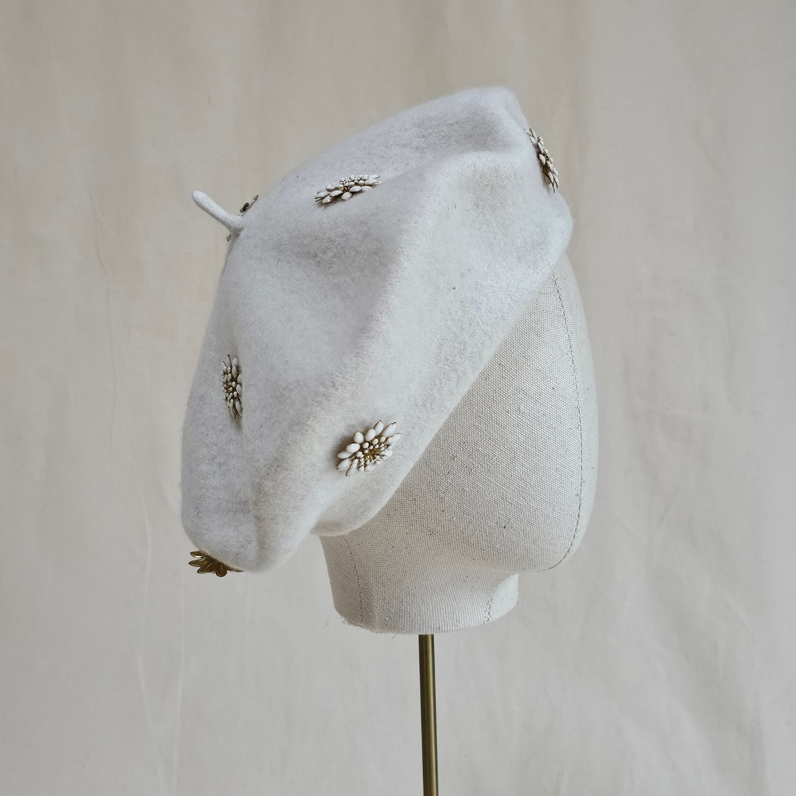 Ivory wool beret with beautiful white daisy embellishments, side view.