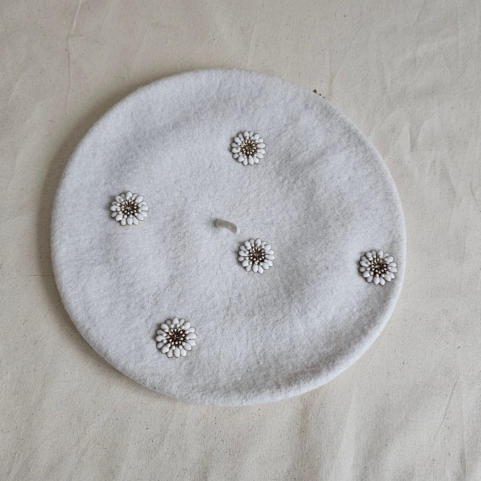 Ivory wool beret with flower embellishments, top view.