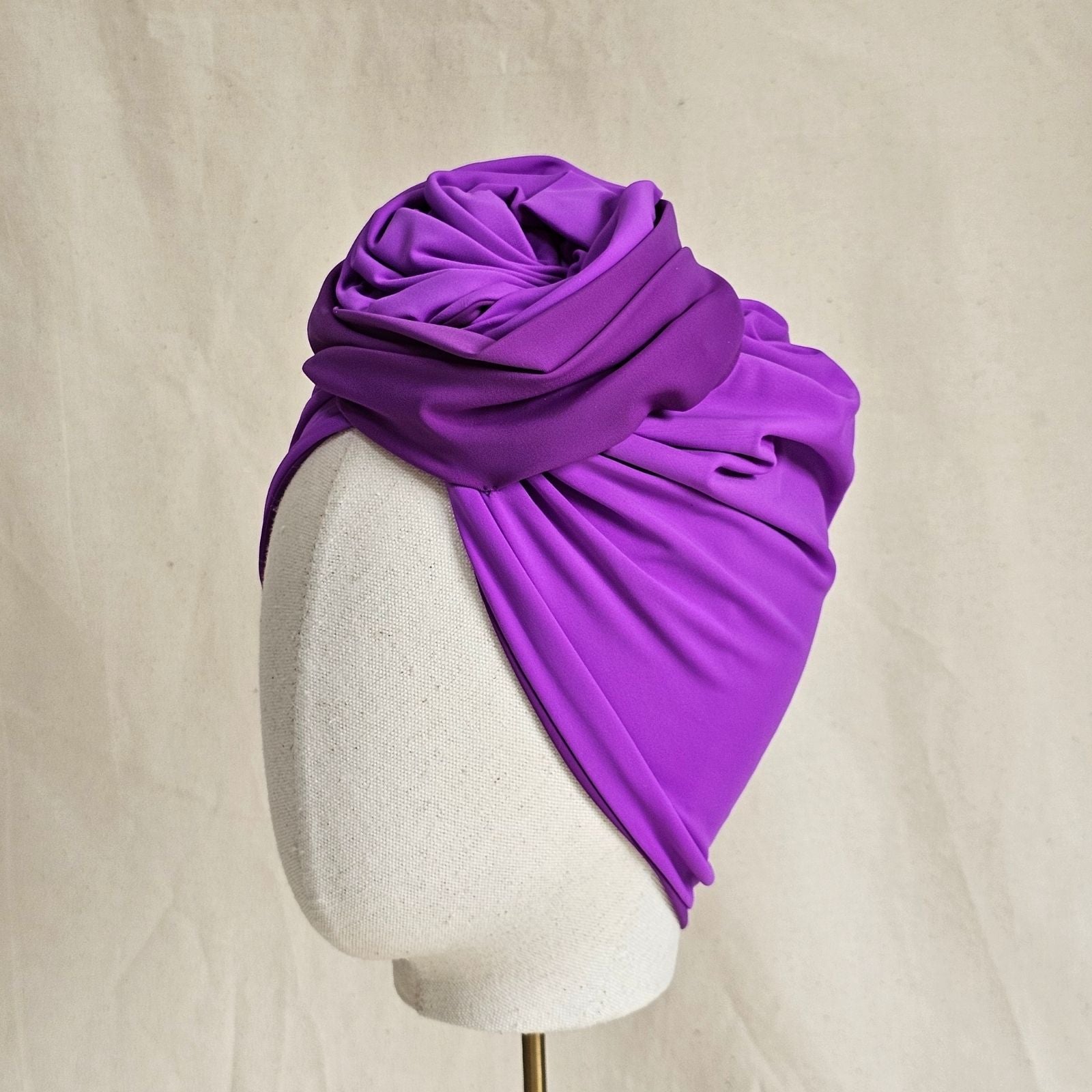 Lilac swim turban with loose gathers and sculpted rose knot, side view.