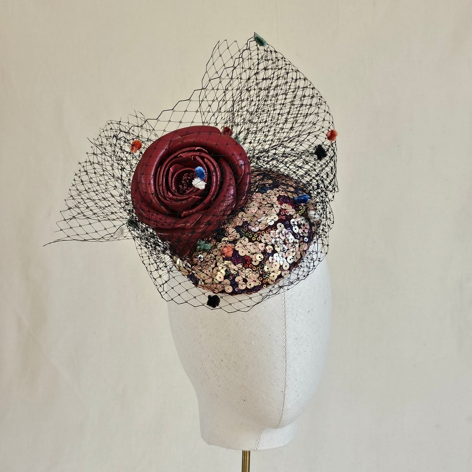 Multicolour sequin mini beret with red rose and spot veiling, front view.