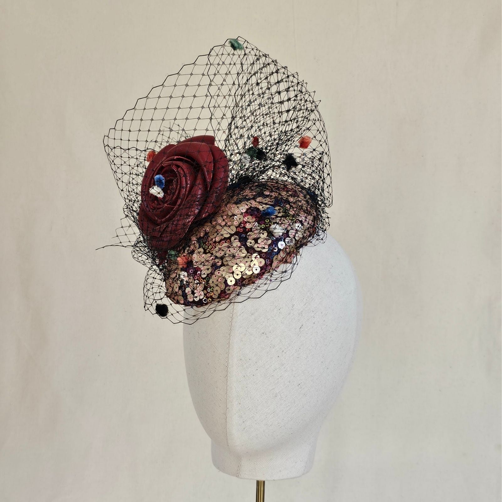 Multicolour sequin mini beret with red rose and dot veiling, left view.